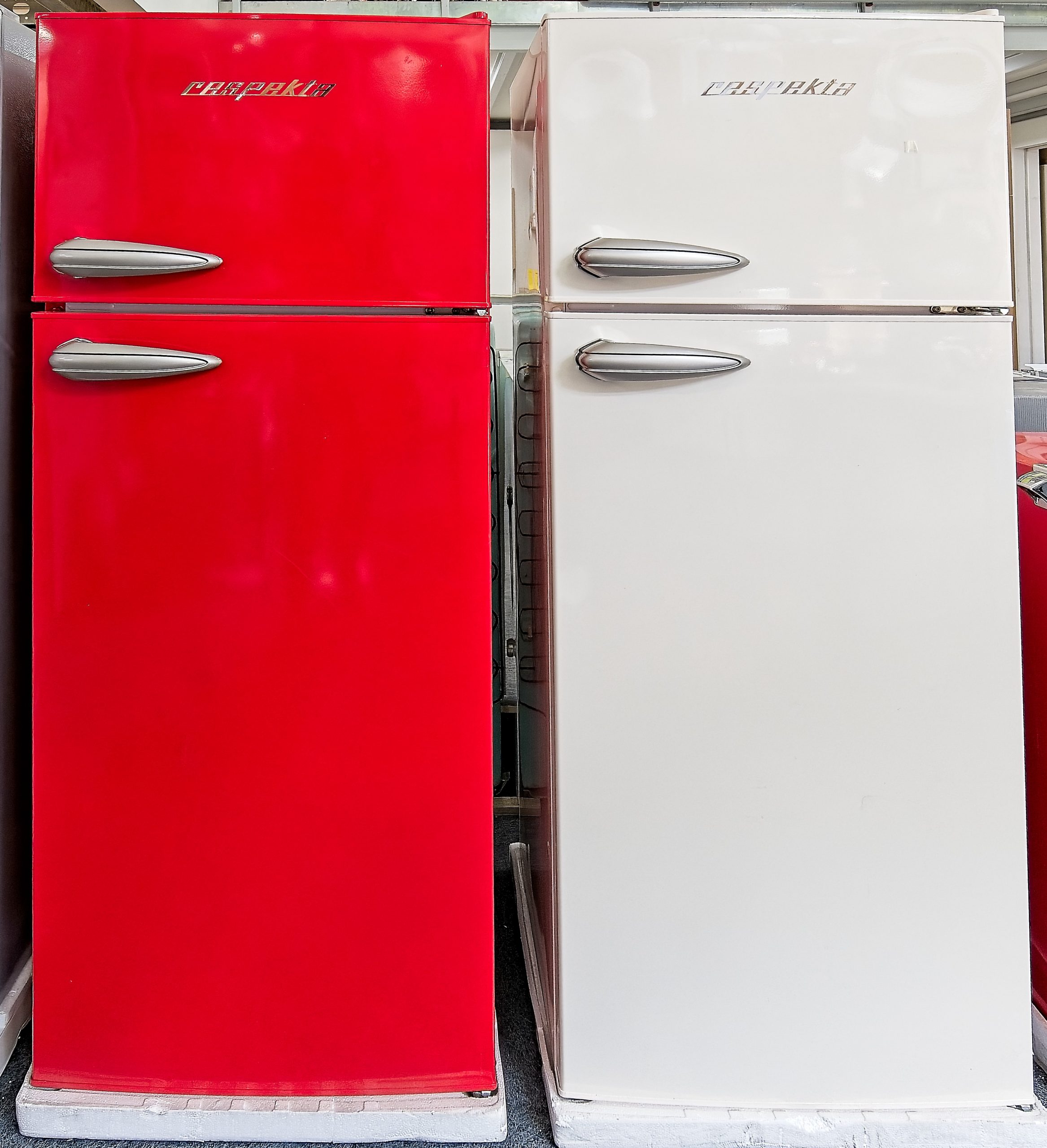 Twee retro koelkasten, rood en wit.